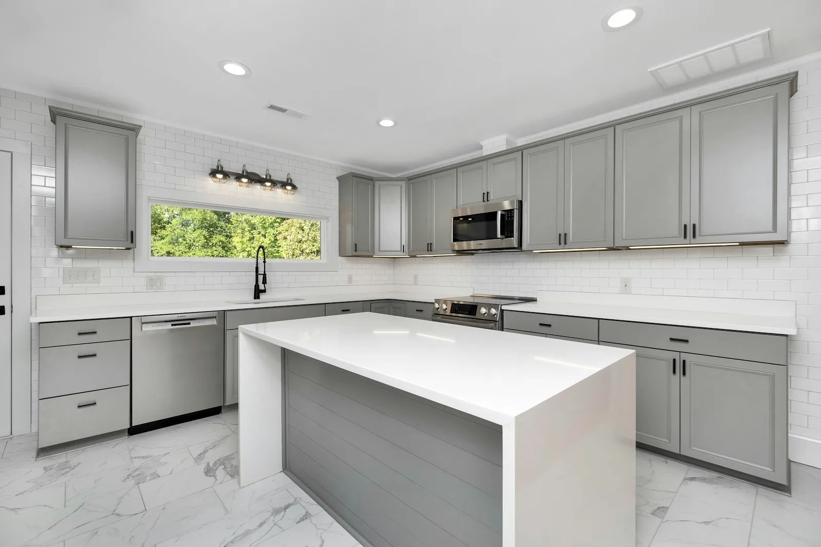 Dapur hasil renovasi dengan kabinet abu-abu, island counter, dan peralatan built-in