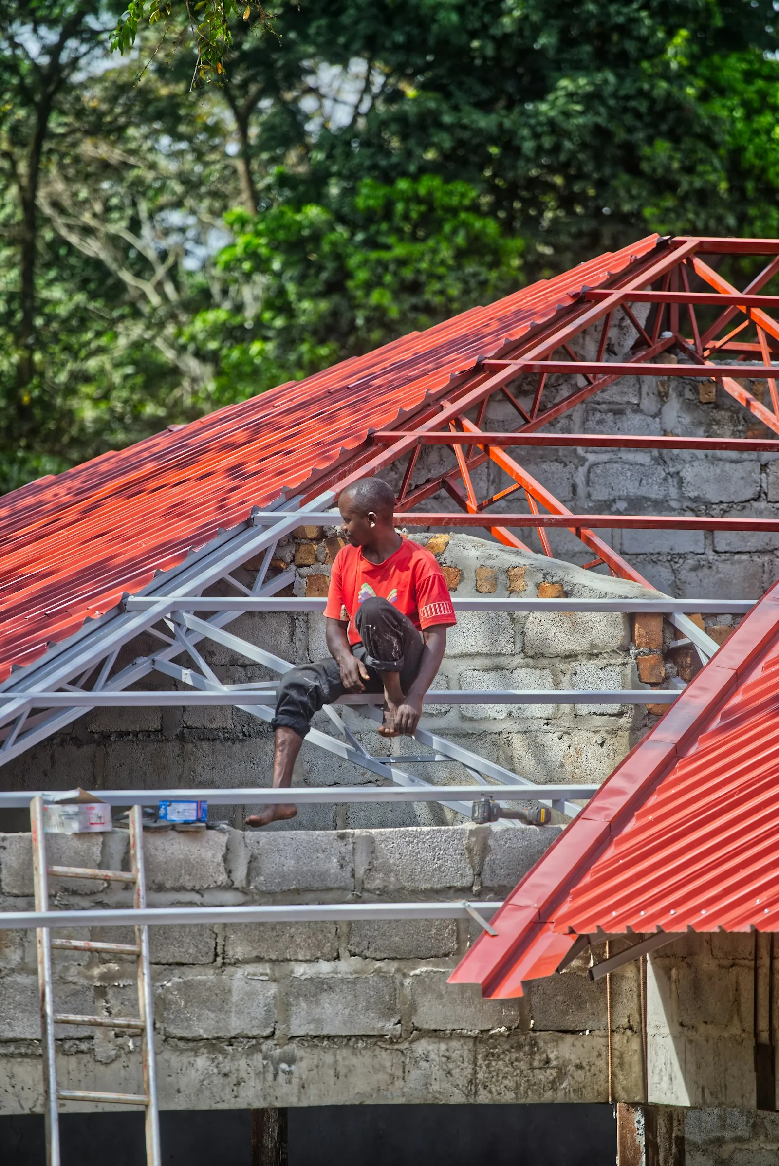 Pekerja memasang genteng metal merah baru pada rangka atap di Ngaliyan