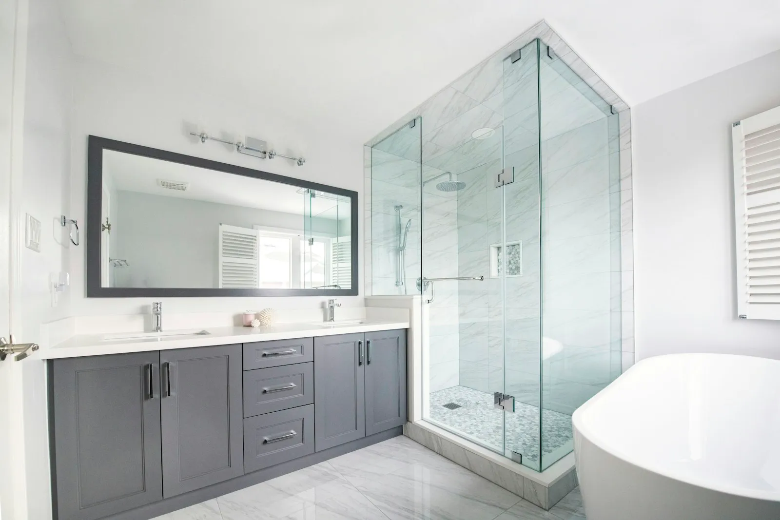 Kamar mandi modern dengan shower kaca frameless dan double vanity abu-abu